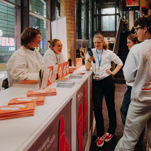 Im Cinestar-Kino stehen Jugendliche mit TV-Mikrofonen in der Hand und lachen miteinander