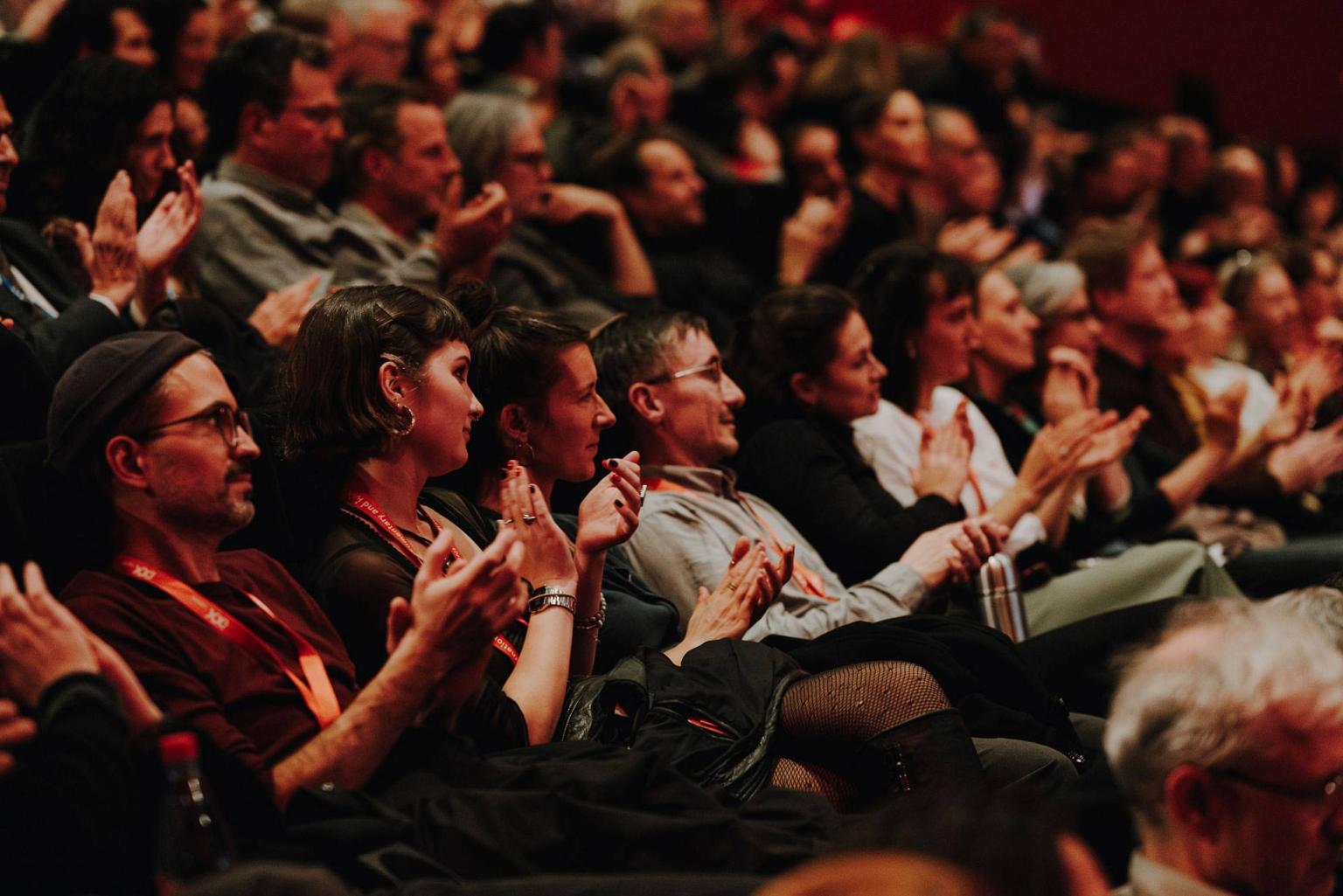 A close up shot of several people in the audience clapping.